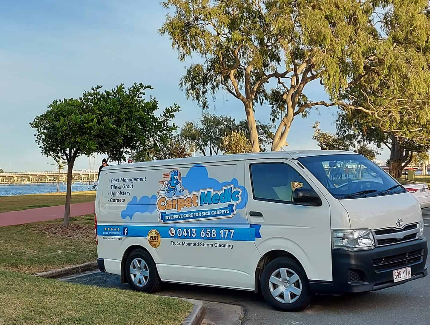 Professional carpet cleaning van parked near a park with trees, promoting Carpet Medic's pest management, tile and grout cleaning, upholstery, and carpet services in Australia.